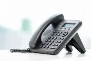 VoIP desk phone in an office by a window